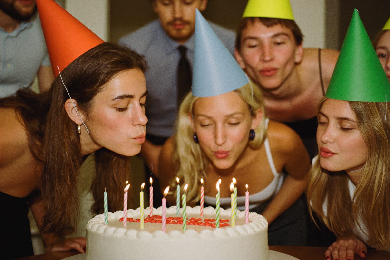 Un groupe en chapeaux de fête souffle les bougies d'un gâteau