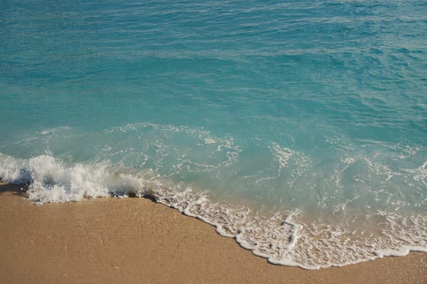 Coucher de soleil sur une mer turquoise, écume sur le sable